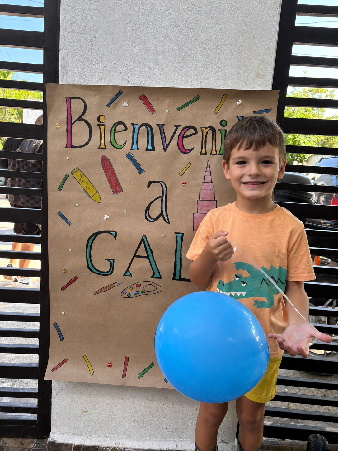 Niño junto al cartel de bienvenida a GAL Montessori School