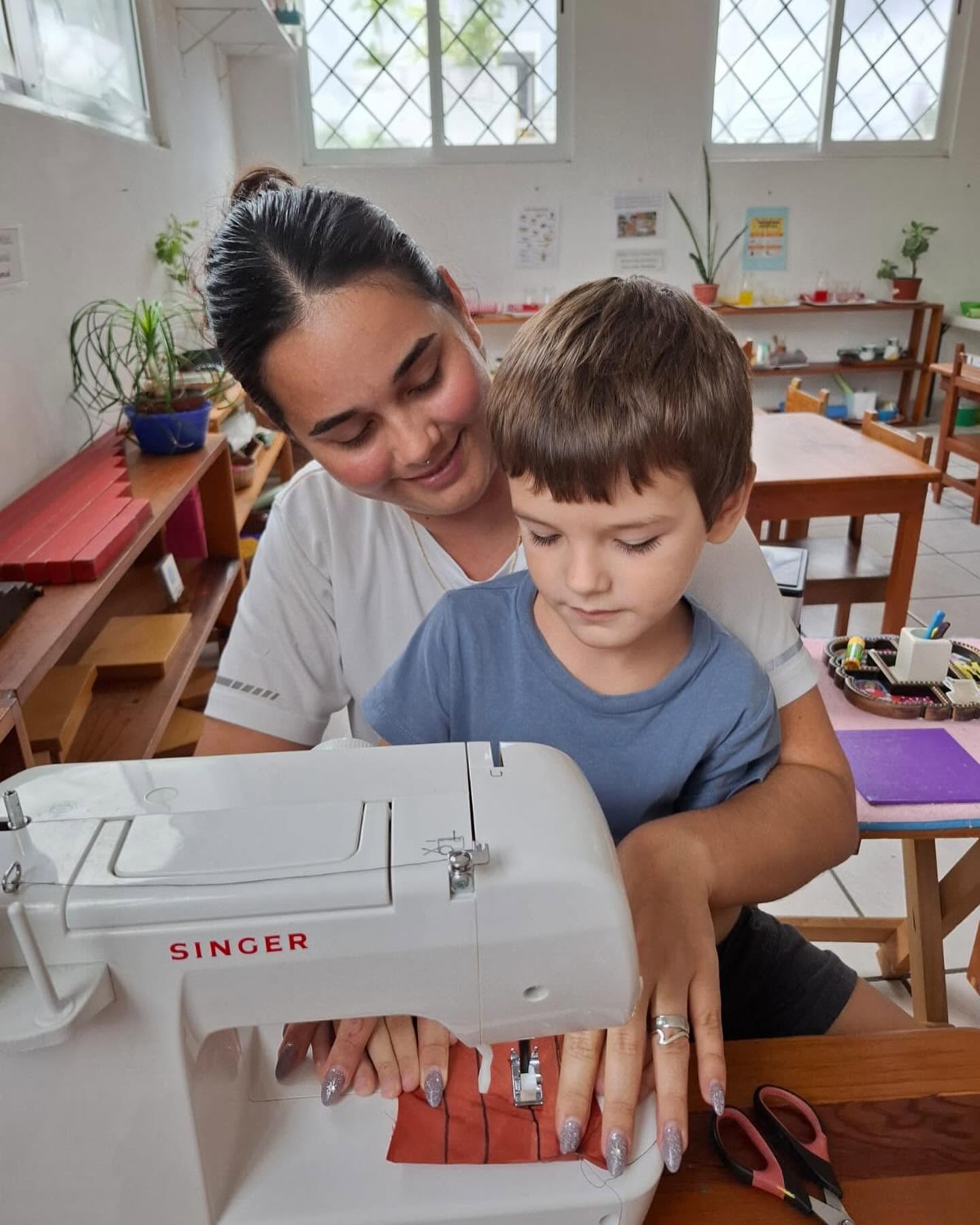 Una guía acompañando con atención el trabajo de un niño