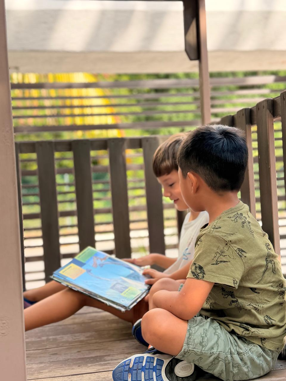 Dos niños compartiendo un libro al aire libre